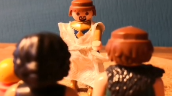 Zwei Playmobilmännchen stehen einem dritten gegenüber.