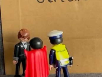 Pappe mit dem Wort 'Gericht' davor zwei Playmobilmännchen , die einen dritten befragen.