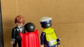 Pappe mit dem Wort 'Gericht' davor zwei Playmobilmännchen , die einen dritten befragen.