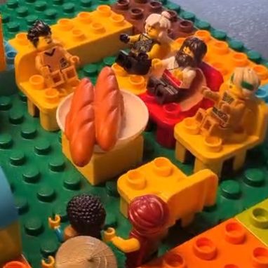 Legomännchen sitzen um einen Tisch mit zwei Broten.